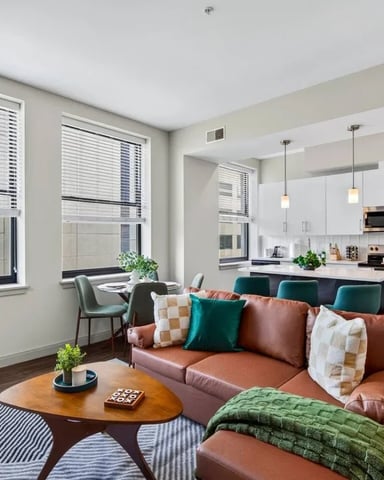 Open-plan living room with terracotta sofa, wooden coffee table, and modern kitchen with white cabinetry and stainless steel appliances