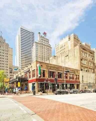 Downtown city plaza with historic and modern buildings, brick paving, and clear blue sky