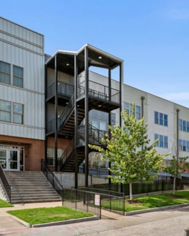 Modern mixed-use building with brick base, metal exterior staircase, and multi-story metal and white siding upper levels