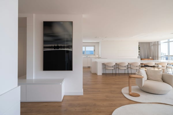 Minimal white open-plan apartment with ocean view, warm wood floors, and clean modern furnishings